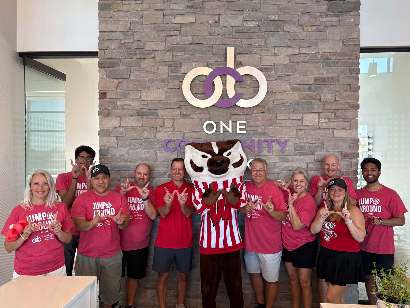 Group photo of OCB-Waunakee colleagues and Bucky Badger in front of OCB-Waunakee sign.