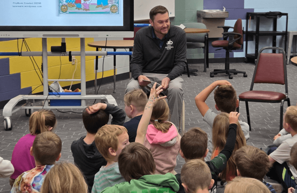 Kyle Drouin reading to a class of elementary school children for Teach Children to Save initiative